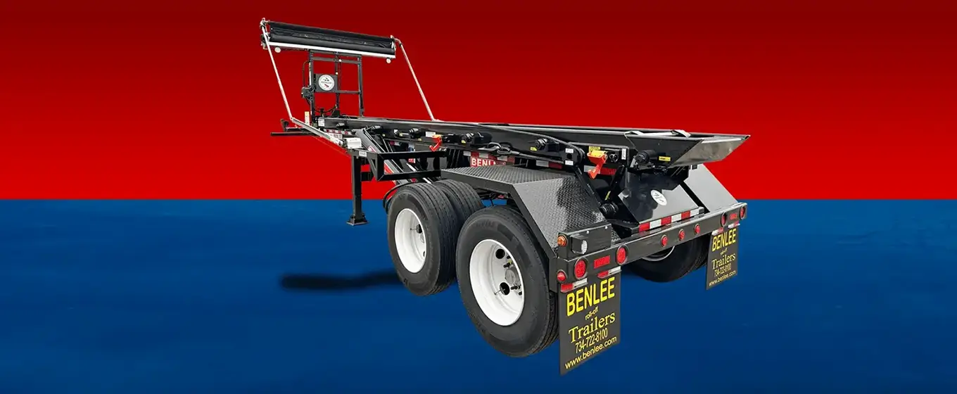 Tiltbed trailer chassis with dual axles and Benlee Trailers signage against a red and blue background; industrial transport equipment view.